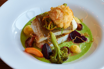 White stewed pikeperch fish in green pesto sauce with vegetables for steaming broccoli, carrots, beets, mushrooms, mashed potatoes