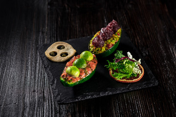 Salmon tartare and avocado salad on a black background