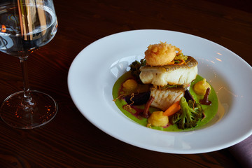 White stewed pikeperch fish in green pesto sauce with vegetables for steaming broccoli, carrots, beets, mushrooms, mashed potatoes , there is a glass with clean water