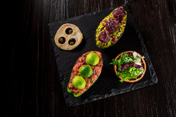 Salmon tartare and avocado salad on a black background