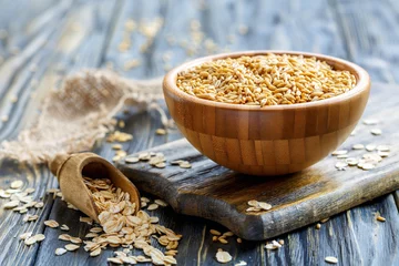 Fototapeten Whole oats in a bowl and oat flakes in a wooden scoop. © sriba3