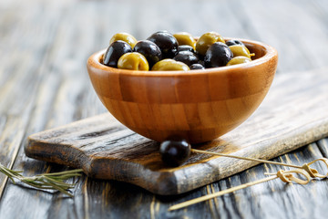 Black and green olives in a wooden bowl.