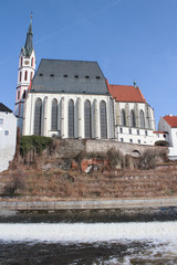 Church in Cesky Krumlov with Vltava river and weir