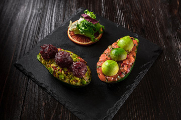 Salmon tartare and avocado salad on a black background