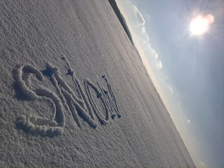 Snow Caption Sunny Sky. Handwritten in the snow surface. Sky and sun in the background.