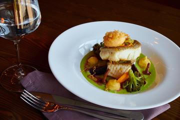 White stewed pikeperch fish in green pesto sauce with vegetables for steaming broccoli, carrots, beets, mushrooms, mashed potatoes , there is a glass with clean water
