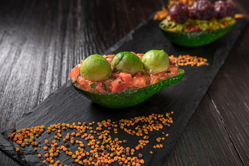 Salmon tartare and avocado salad on a black background