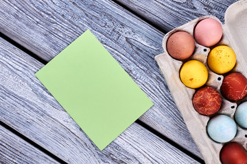 Paper card and eggs. Dyed eggs on grey background. Traditional Easter attributes.