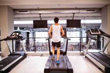 Young fit hispanic man in gym running on treadmill.