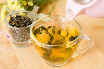 Pouring hot tea from teapot into a cup, healthy drink