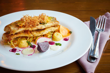 Baked cod fillet with vegetables in restaurant interior