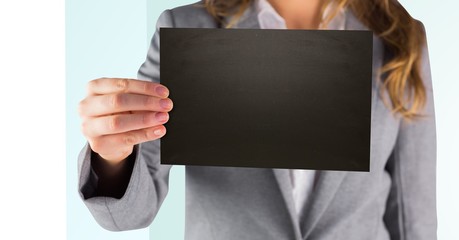 Business woman holding out black blank card against white and green background
