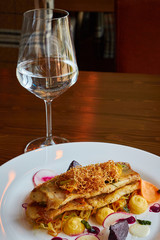 Baked cod fillet with vegetables in restaurant interior