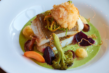 White stewed pikeperch fish in green pesto sauce with vegetables for steaming broccoli, carrots, beets, mushrooms, mashed potatoes close up