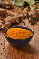 Ground turmeric powder in a bowl on wooden background. Healthy spice.