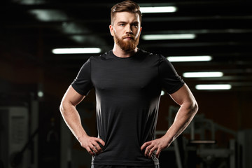 Fototapeta na wymiar Serious sports man standing and posing in gym