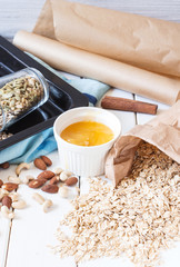 Ingredients for granola, oat flakes, nuts, seeds on a white wooden background, vertical horizontal, selective focus
