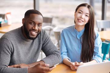 Young man and woman using smartphones at cafe