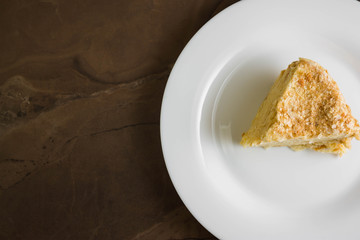 Piece of cake with butter cream on a white plate. Napoleon cake. A delicious dessert.