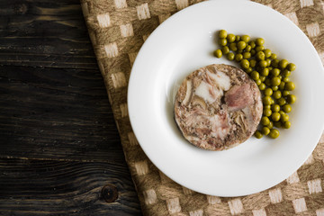 Headcheese with peas on a wooden table. Tasty and nutritious dish.