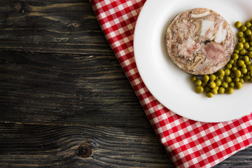 Fototapeta na wymiar Headcheese with peas on a wooden table. Tasty and nutritious dish.