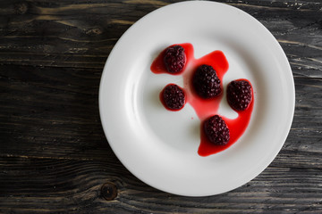 Blackberry in a white plate on a wooden table.
