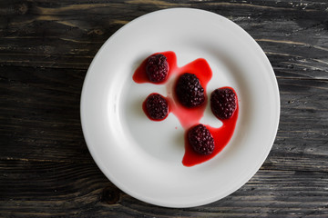 Blackberry in a white plate on a wooden table.
