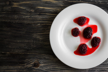 Blackberry in a white plate on a wooden table.
