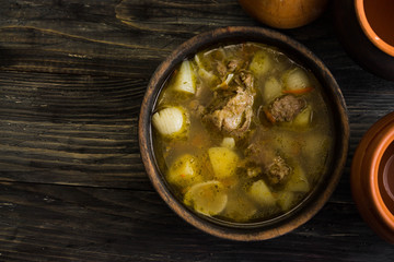 Soup with meat in a wooden bowl on a wooden table. Tasty and nutritious dish.