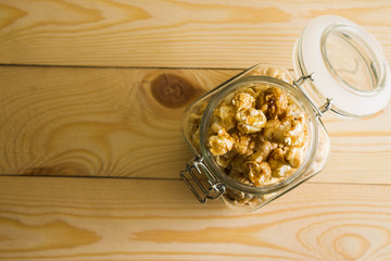 Popcorn in a glass jar on a wooden table.