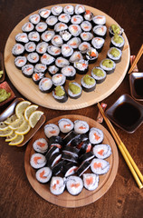 Homemade sushi rolls. Sticks, lemon, soy sauce, wasabi are served on a dark brown wooden table