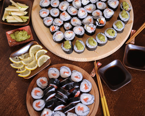 Homemade sushi rolls. Sticks, lemon, soy sauce, wasabi are served on a dark brown wooden table