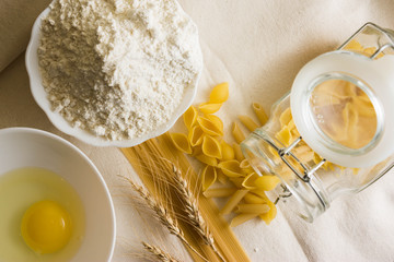 Raw pasta on a white sacking and ingredients. Different types of pasta.