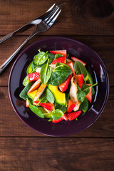 Healthy salad plate with avocado, strawberry, chicken and spinach on wooden background top view. Food and health. Clean eating.