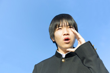 遠くを見つめ叫ぶ男子高校生