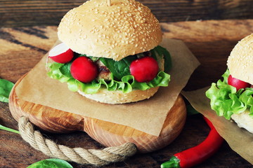 Homemade traditional burgers with beef,radish,lettuce, served on wooden background.