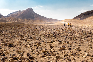 Three backpackers walking stone desert trail.