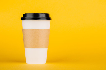 Paper coffee container with black lid on yellow background