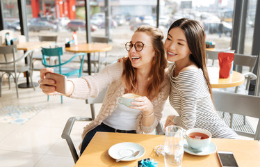 Two girlfriends doing selfie at cafe