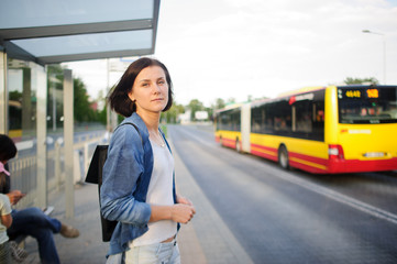 The young woman the brunette stands on the bus stop.
