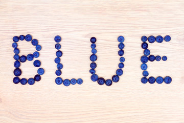 Healthy food. Word "blue" made of  blueberries isolated on beige background