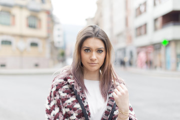 Portrait of serious beautiful young woman in the street.