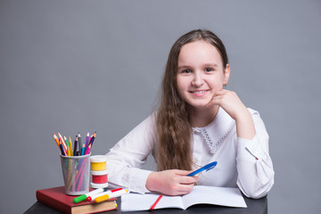 A schoolgirl sits at her desk and does homework