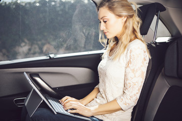 Beautiful woman sitting in the car with a computer