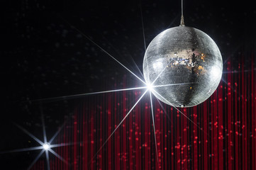 Party disco ball with stars in nightclub with striped red and black walls lit by spotlight,...