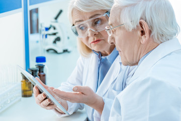 Senior couple of scientists working with digital tablet in lab