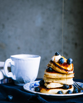 Pouring syrup on blueberry pancakes 