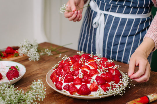 Woman decorating cake in stawberries and gypsophila 