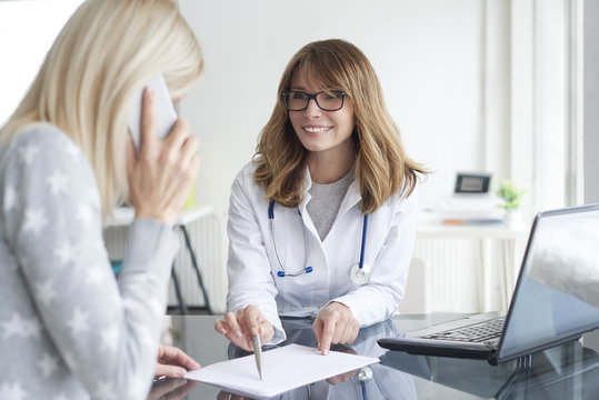 Doctor and her patient. Shot of a middle aged female doctor sitting in front of laptop and consulting with her patient.