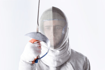 Close-up view of young man professional fencer holding rapier on white